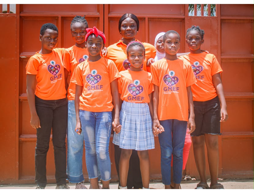 A group of GMEF learners and a facilitator wearing GMEF shirts.